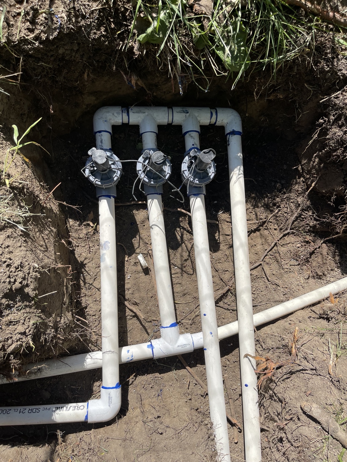 Three-valve PVC manifold tied into the mainline in a Benton City trench