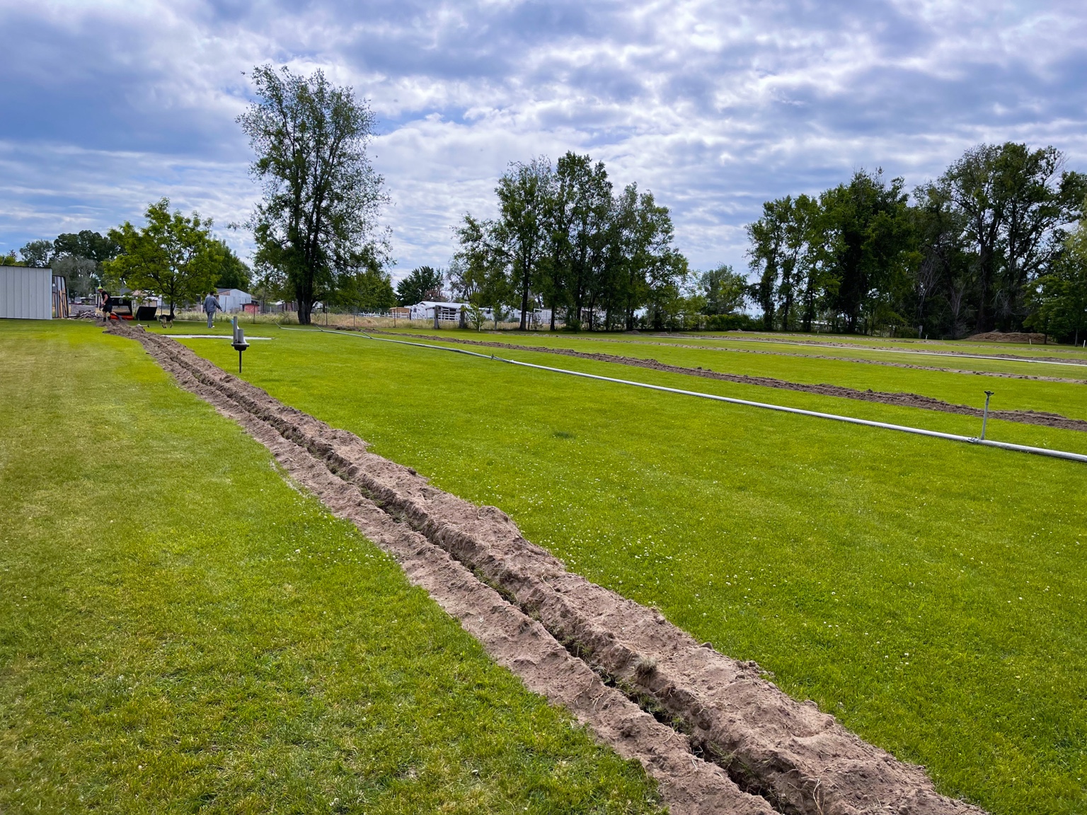 Long clean trencher cuts running across a green lawn on a large Kennewick property