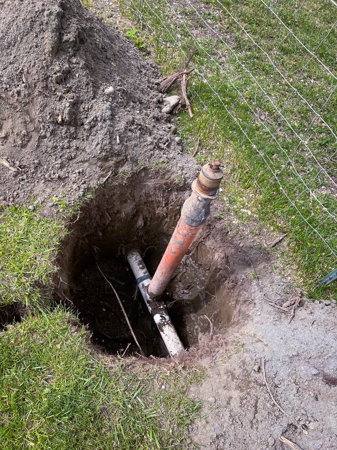 Deep pit exposing an old orange riser tied into a fresh PVC mainline repair in Pasco