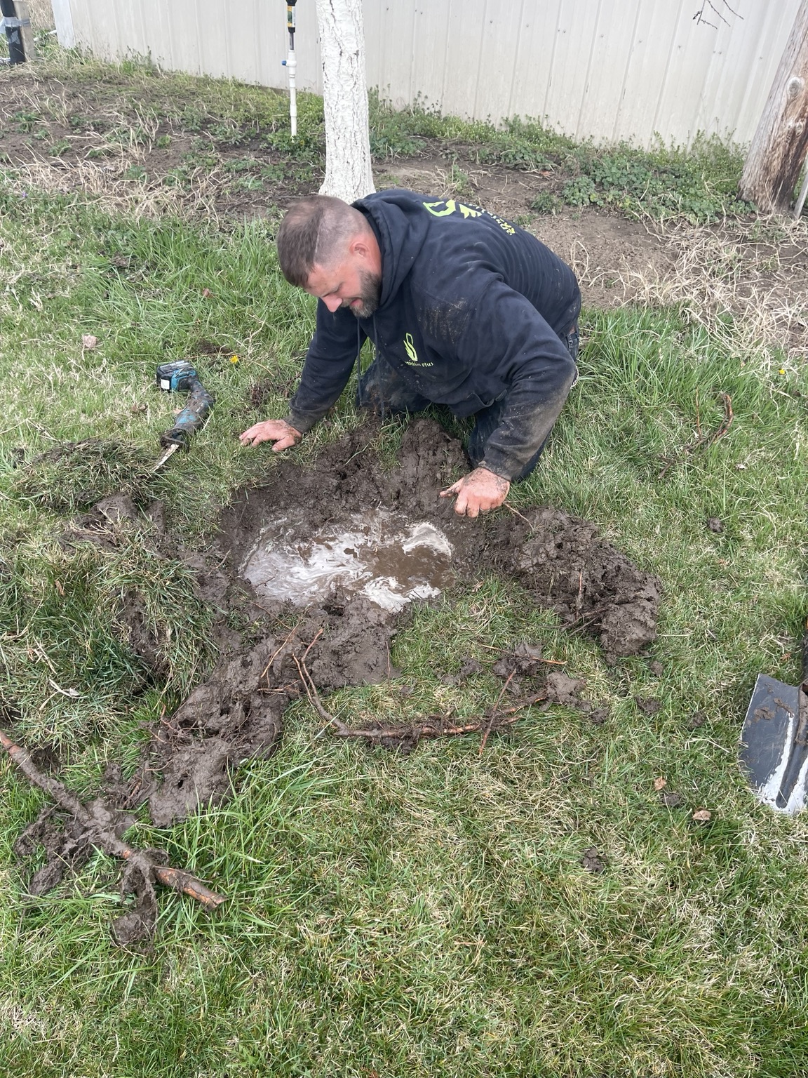 Sprinkler Plus tech digging out a saturated underground leak in a Pasco lawn