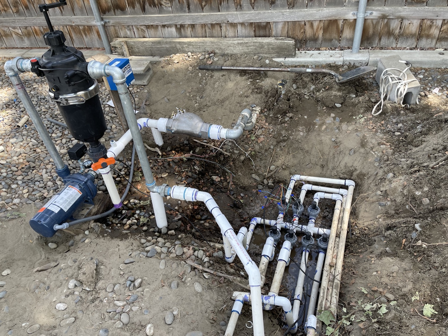 Complete pump, filter, and valve manifold assembly staged in a backyard pit