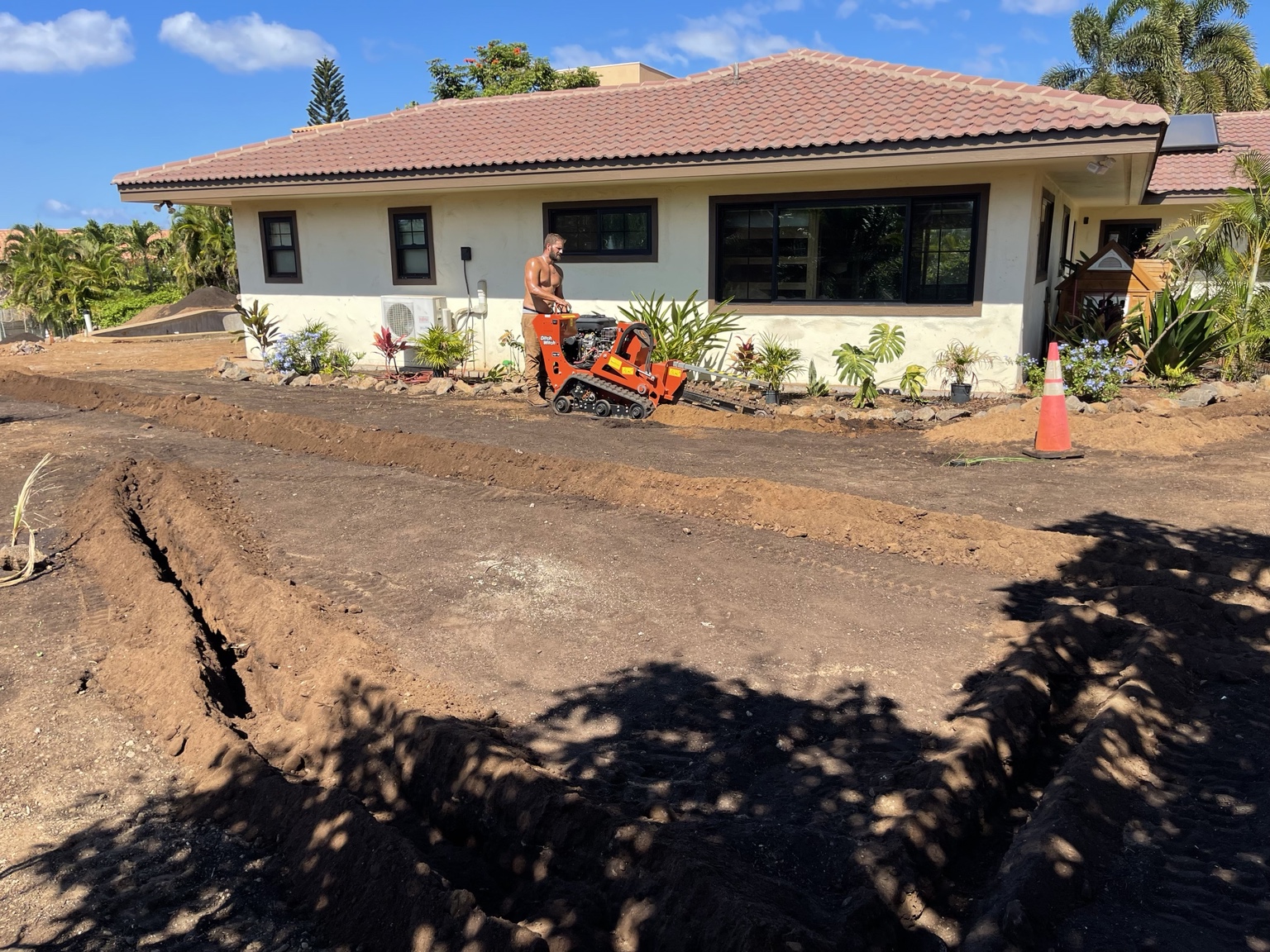 Sprinkler Plus operator running a Ditch Witch trencher around a home