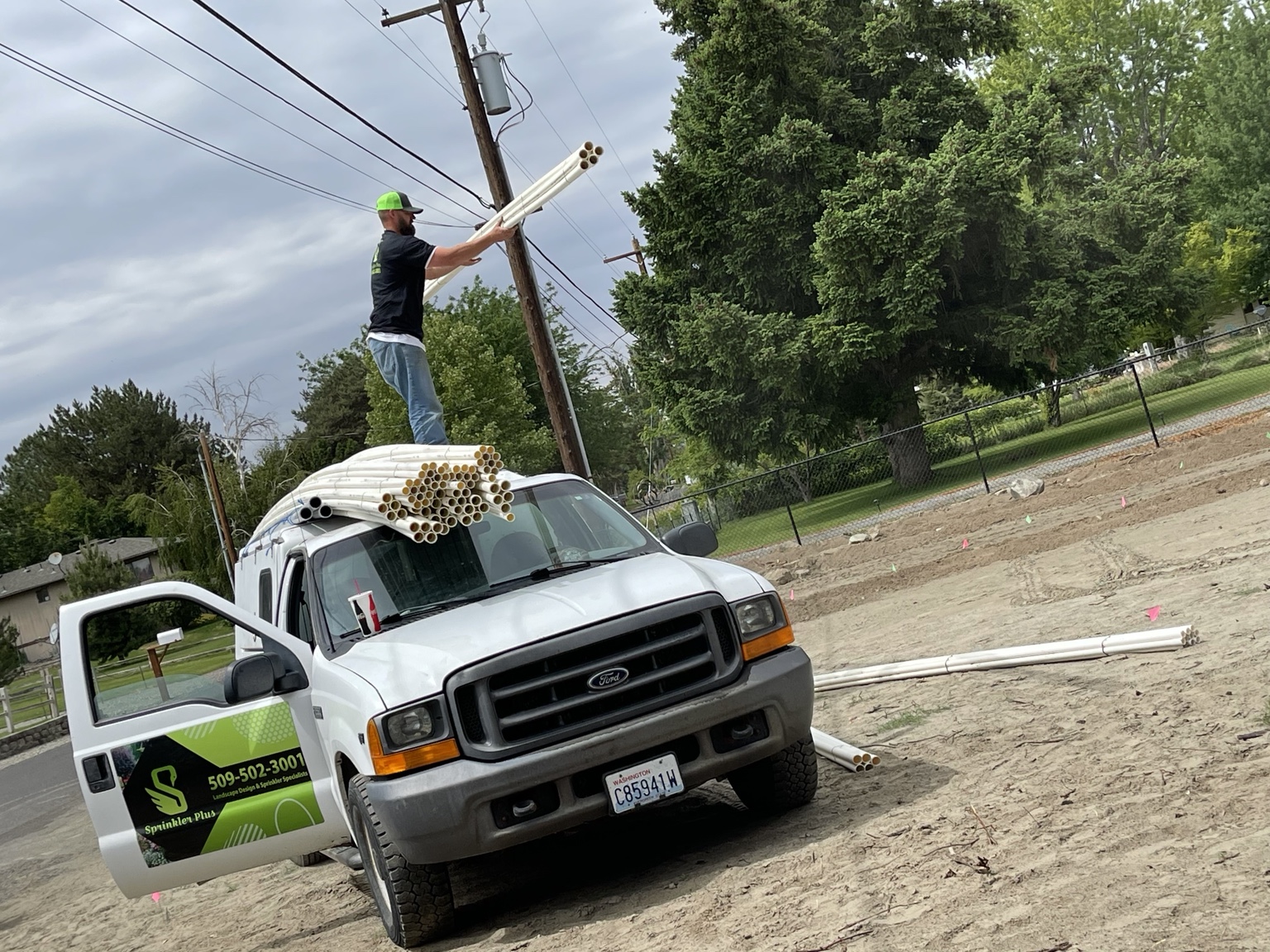 Sprinkler Plus tech loading bundles of PVC pipe off a wrapped service truck