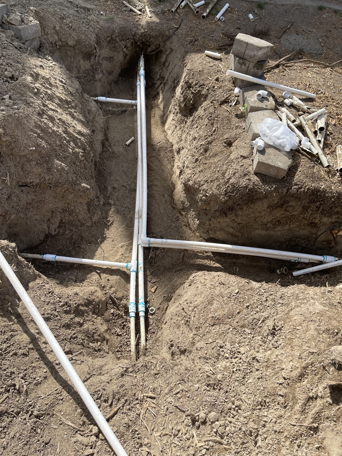 Overhead view of a full PVC manifold with primed joints in a trench