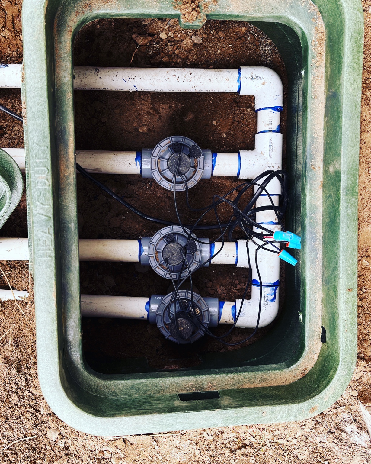 Overhead view inside a heavy-duty valve box showing three solenoid valves and wiring