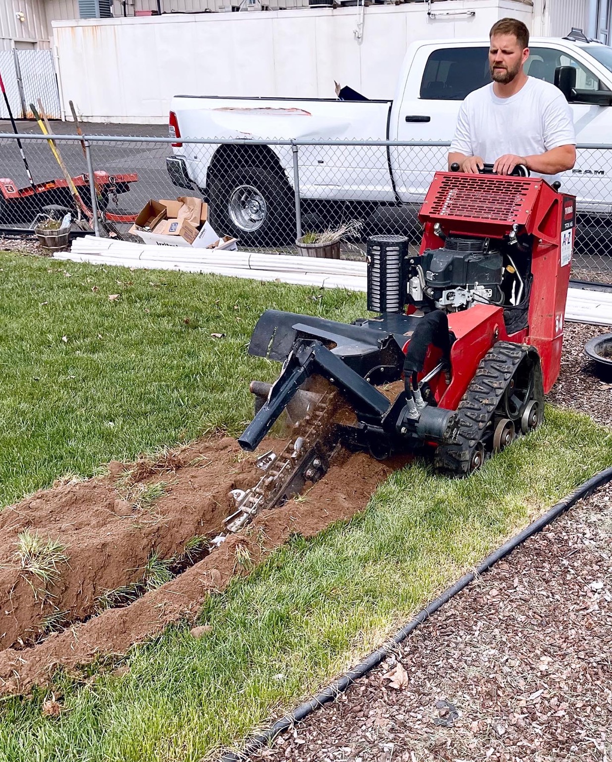 Sprinkler Plus crew running a walk-behind trencher through a lawn
